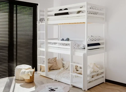 Minimalistisk værelse med hvid tredobbelt køjeseng, mørke persienner, puf og rundt tæppe