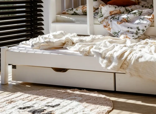 Nærbillede af udtræksseng med to rummelige opbevaringsskuffer under, ved siden af et børnetæppe.