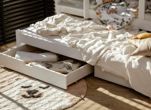 Åben opbevaringsskuffe under udtrækssengen, viser plads til tøj og legetøj. Nem adgang til ting.