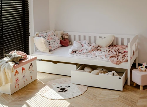 Lyst børneværelse med hvid daybed med udtræksskuffer, legetøjskiste og rundt tæppe.