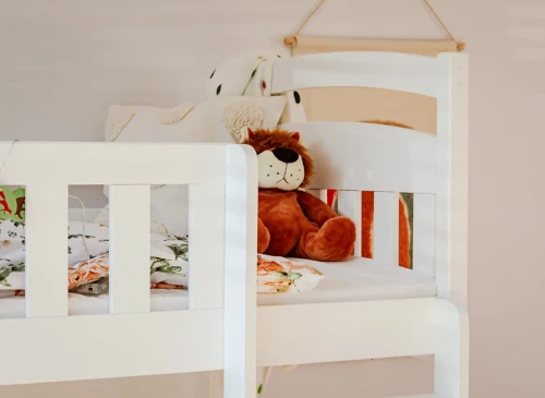 Nærbillede af øverste køje på hvid køjeseng med bamse og sengetøj med skovmotiv.