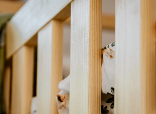 Detalje af sengehest i lyst naturligt træ, der viser træets struktur og finish.