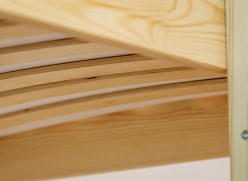 Nærbillede af lamelbund under madras i en sengeramme af lyst træ.