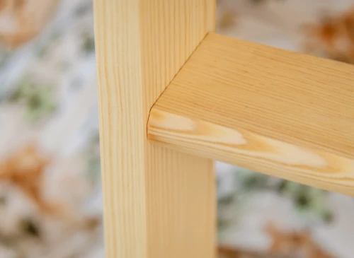 Glat hjørnesamling i sengeramme af lyst træ, med fine årestrukturer og præcis udførelse.