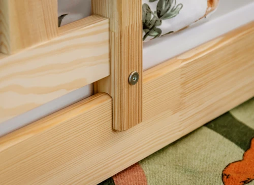 Nærbillede af træsengsforbindelse med synlig metalbolt og robust konstruktion.