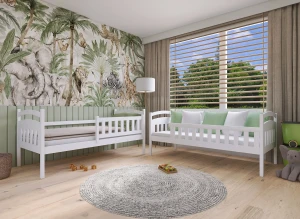 To hvide børnesenge i et værelse med jungle-tapet, tæppe og stort vindue.