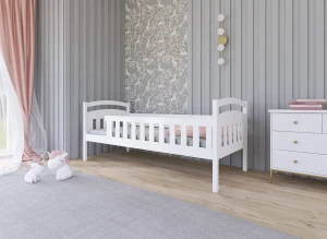 Hvid tremmeseng i minimalistisk design til småbørn, med kommode og tæppe i et moderne børneværelse.