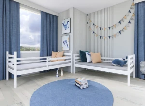 To hvide enkeltsenge i børneværelse med blå gardiner, hvalkunst og rundt tæppe.