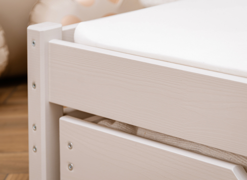 Nærbillede af en lys træsengeramme med synlige årer og en hvid madras, kvalitet og design.