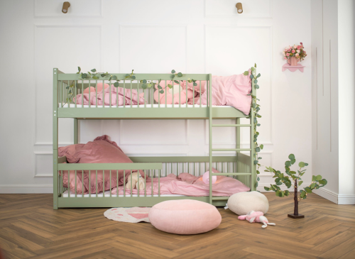Smuk grøn køjeseng med lyserødt sengetøj i et lyst børneværelse, komplet med dekorative elementer.