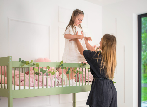 Mor hjælper datter med at stå på den øverste køjeseng, begge giver thumbs up. Leg og sikkerhed.