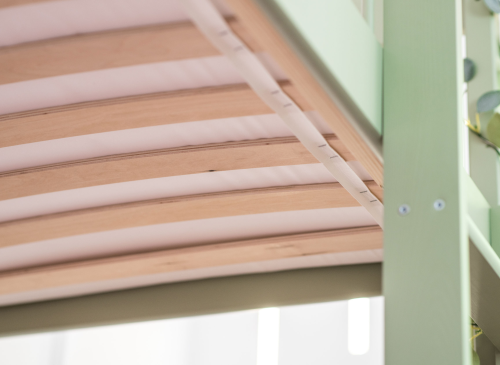 Detaljebillede af en robust lamelbund i en grøn børneseng. Komfort og støtte til barnet.