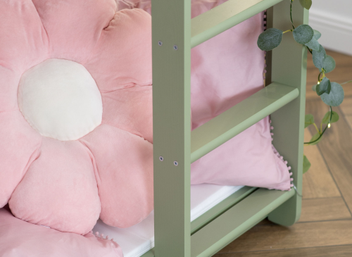 Nærbillede af en lyserød blomsterpude på en grøn børneseng. Sødt og dekorativt tilbehør.