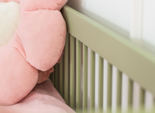 Detalje af sengehesten på en grøn køjeseng med lyserødt sengetøj. Sikkerhed og design kombineret.