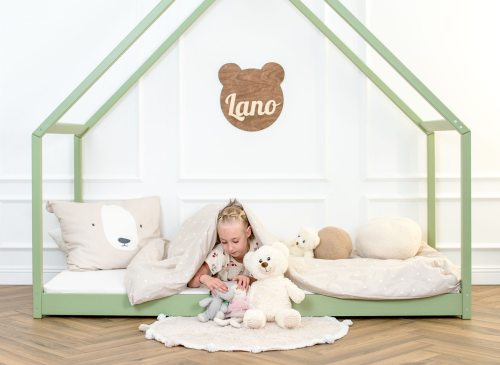 Pige leger med bamser under dynen i grøn husseng, hygge og leg.