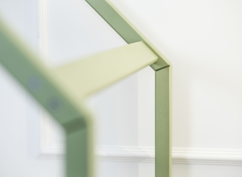Nærbillede af den lysegrønne træramme på en husformet seng. Minimalistisk børneværelsesdesign.