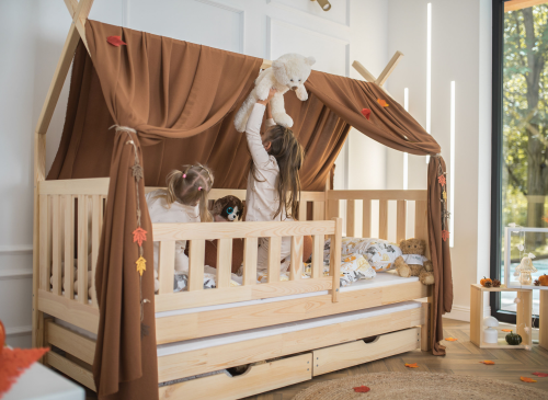 To piger leger i en træ-husseng med brun himmel, udtræksseng og opbevaring. Ideel til børneværelset.