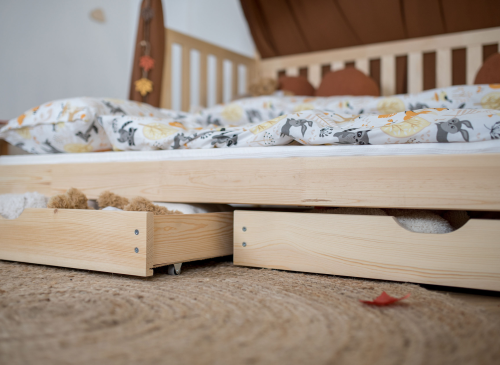 Nærbillede af udtræksskuffer under juniorseng i naturtræ. Opbevaringsløsning til børneværelset.