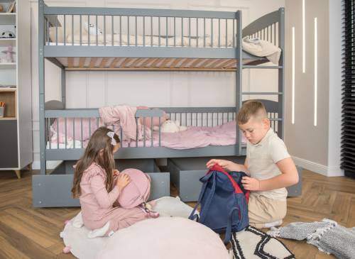 Børn pakker tasker i et værelse med en grå køjeseng og pink sengetøj.