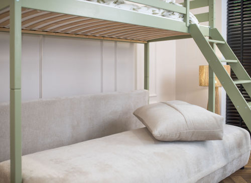 Nærbillede af den beige sovesofa under den grønne køjeseng med en pude.