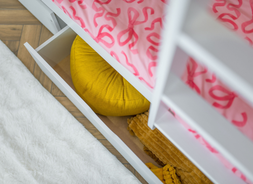 Opbevaringsskuffe under hvid køjeseng med gult tæppe og pude.