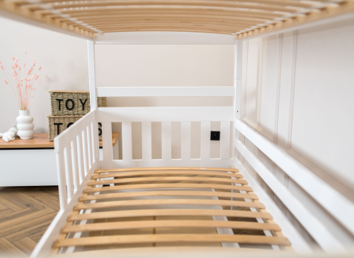 Detalje af lamelbund og hvid træramme på en solid køjeseng til børn.