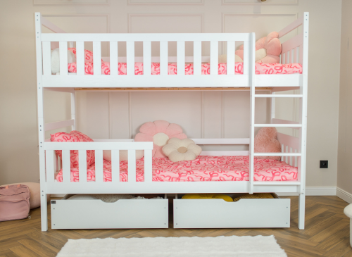 Hvid køjeseng til børn med indbyggede skuffer og lyserødt sengetøj i et lyst værelse.